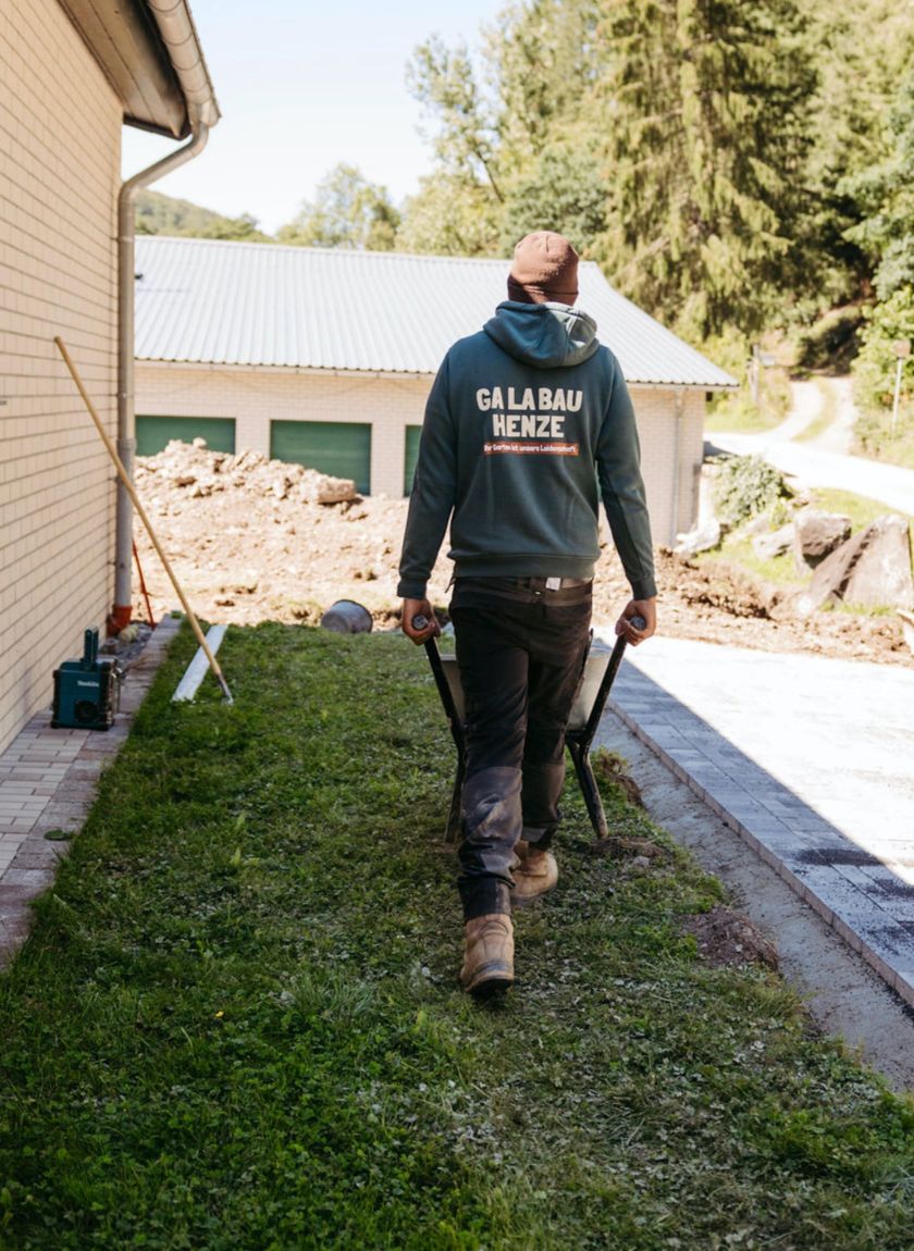 mitarbeiter-galabau-henze-im-sauerland-auf-einem-rasen-mit-einer-schubkarre