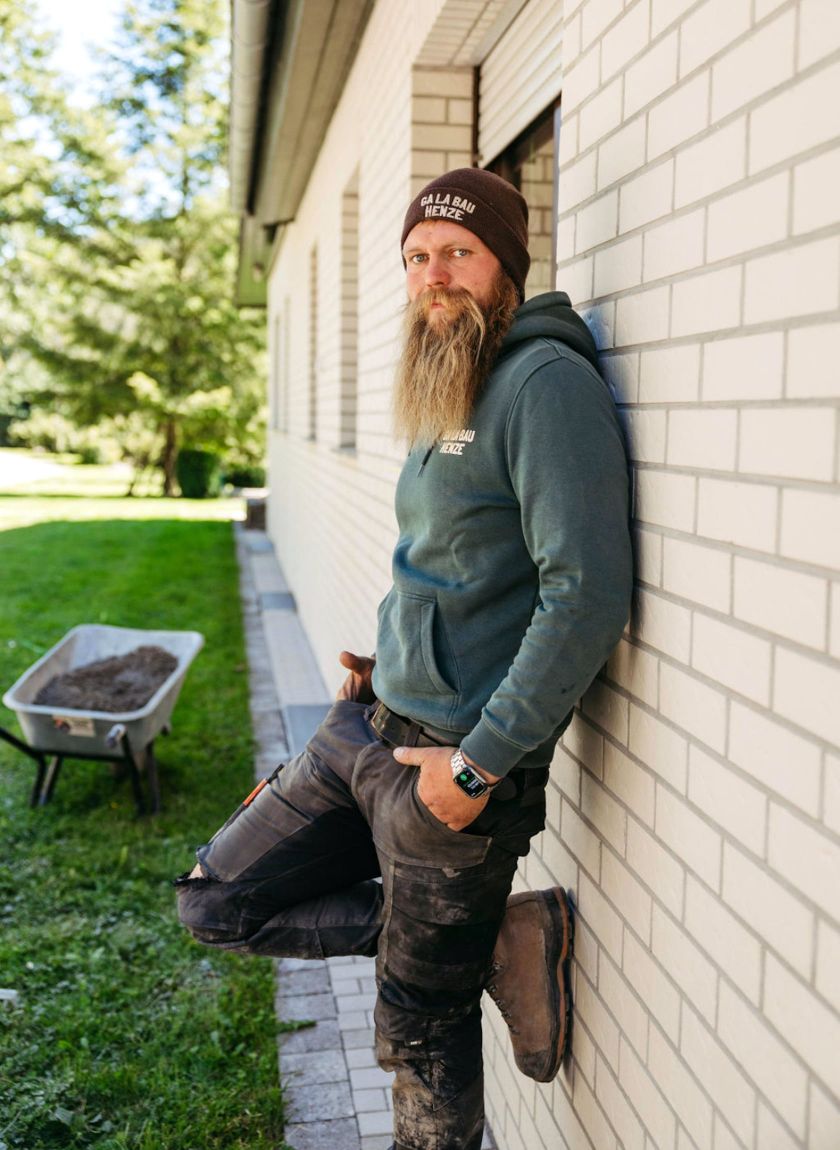 inhaber-galabau-henze-im-sauerland-vor-einer-mauer-und-einer-schubkarre